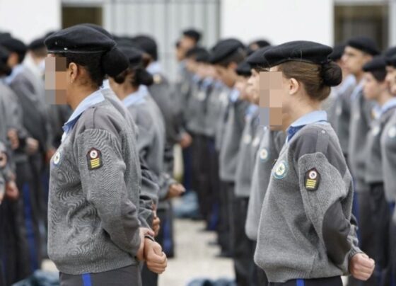 imagem colorida mostra pessoas vestidas com uniforme de escola militar, enfileiradas e com as mãos para trás - metrópoles