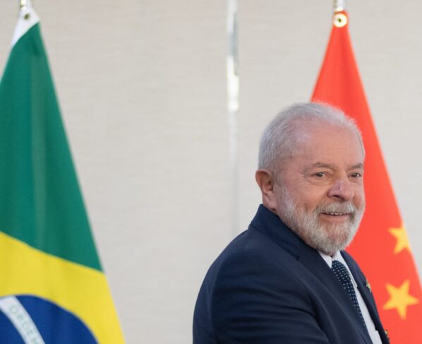 Imagem colorida de Lula com as bandeiras brasileira e chinesa ao fundo