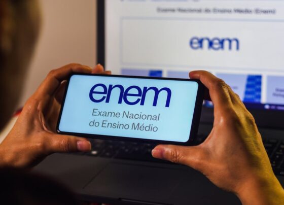 Imagem de pessoa segurando um telefone com a logo do Enem - Metrópoles
